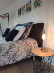 a bed with pillows and a table with a lamp at La Tourelle Suite Cosy entre vignoble aixois et Luberon in Le Puy-Sainte-Réparade