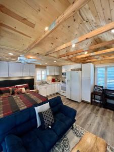 sala de estar con sofá azul y cocina en The Lake Alfred Citruswood Cabin, en Lake Alfred