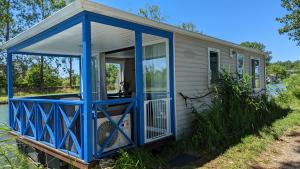una casa pequeña con un porche pintado de azul en Cottage flottant terrasse gamme supérieure option jacuzzi proche Dijon 
