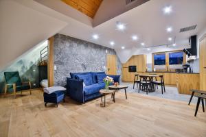 a living room with a blue couch and a stone wall at Domki Nad Osadą in Czorsztyn