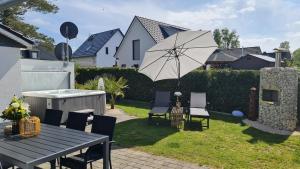 un patio con mesa, sillas y sombrilla en Luxusferienhaus Seevilla Monaco am Fleesensee, en Göhren-Lebbin
