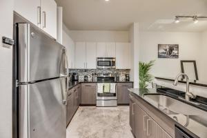 a kitchen with a stainless steel refrigerator and a sink at Trendy 2BR I Pool I Gym I Free Parking I Workspace in Dallas