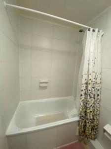 a white bathroom with a tub with a shower curtain at Acogedor dpto en puerto varas in Puerto Varas