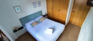 a small bedroom with a white bed with a blue headboard at Apartamento Minairons Espot in Espot