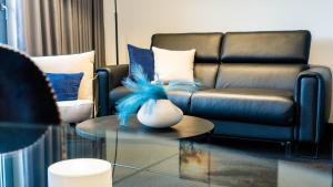 a living room with a leather couch and a table at Kras Resort Apartament 110 z prywatnym jacuzzi i widokiem na góry in Szklarska Poręba