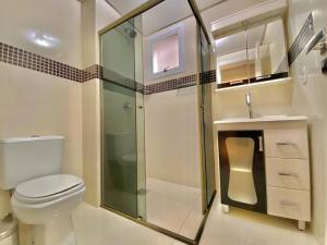 uma casa de banho com um WC e uma cabina de duche em vidro. em Apartamento com fácil acesso ao Vale dos Vinhedos em Bento Gonçalves
