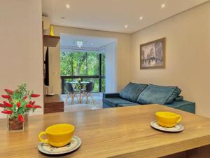 uma sala de estar com uma mesa com duas chávenas amarelas em Apartamento com fácil acesso ao Vale dos Vinhedos em Bento Gonçalves