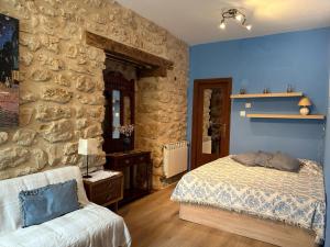 1 dormitorio con cama y pared de piedra en La Venta de Izan, en Gumiel de Hizán