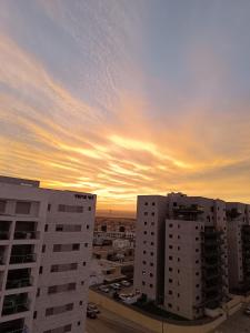 a sunset over a city with tall buildings at Lovely room at Benny's apartment in Netivot