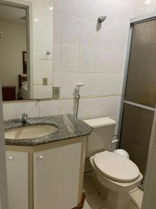 a bathroom with a toilet and a sink and a mirror at APTO PRAIA DO MORRO, 02 QUARTOS C SUITE, WI-FI, GARAGEM, 1 ANDAR ESCADA. in Guarapari