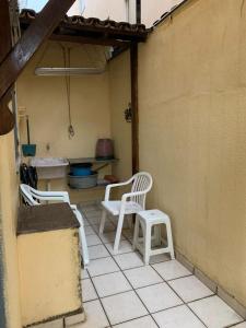 eine Terrasse mit zwei weißen Stühlen und einem Tisch in der Unterkunft APTO PRAIA DO MORRO, 02 QUARTOS C SUITE, WI-FI, GARAGEM, 1 ANDAR ESCADA. in Guarapari