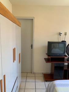 una habitación con TV en una mesa junto a una puerta en APTO PRAIA DO MORRO, 02 QUARTOS C SUITE, WI-FI, GARAGEM, 1 ANDAR ESCADA. en Guarapari