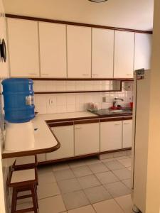 una cocina con armarios blancos y un cubo azul sobre una mesa en APTO PRAIA DO MORRO, 02 QUARTOS C SUITE, WI-FI, GARAGEM, 1 ANDAR ESCADA., en Guarapari