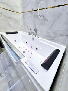 baño de mármol blanco con bañera blanca. en Apartament Chill & Lux, en Ostróda
