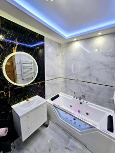 een badkamer met een bad, een wastafel en een spiegel bij Apartament Chill & Lux in Ostróda