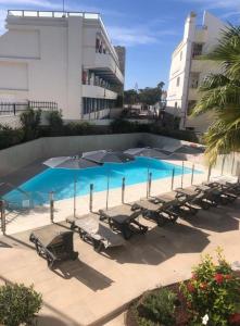 a group of lounge chairs and umbrellas next to a pool at Apartamento en Playa del Inglés Los Mangos in Playa del Ingles