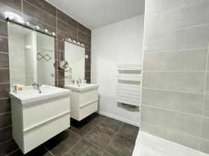 La salle de bains est pourvue de 2 lavabos et d'un miroir. dans l'établissement Chaleureuse maison avec terrasse et garage, à Espira-de-lʼAgly