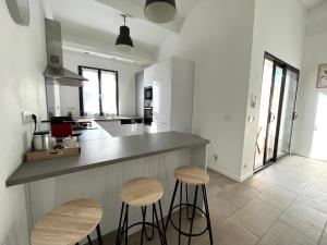 une cuisine avec deux tabourets et un comptoir dans l'établissement Chaleureuse maison avec terrasse et garage, à Espira-de-lʼAgly