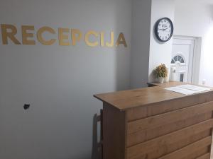 a reception desk with a clock on a wall at Apartmani Centar in Sjenica