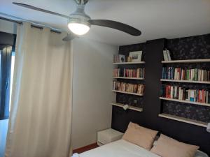 a bedroom with a ceiling fan and bookshelves at Casa del Doctor in Seville