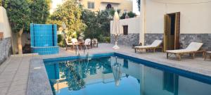 a swimming pool with chairs and a table and a umbrella at Senmut Luxory Apartments in Luxor