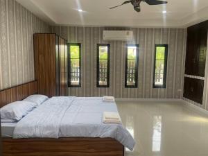 a bedroom with a large bed and three windows at The phoenix kanchanaburi in Kanchanaburi