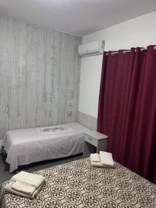 a room with two beds and a purple curtain at Nina's house 2, a 300 metri dal mare in Santa Caterina Dello Ionio Marina