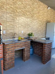 uma cozinha com um lavatório e uma parede de tijolos em Chácara Casa da Paz em Suzano