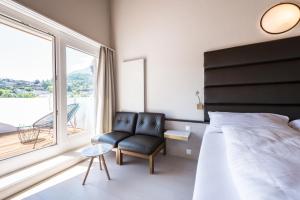 a bedroom with a bed and a chair and a window at Boutique Hotel Riviera in Spiez