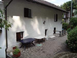 a white house with a table and a bench at Ostello Orgnana in Magadino