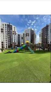 a playground with a slide in a park with tall buildings at Аэропорт-Номера 24/24 . in Chişinău