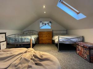 a attic bedroom with two beds and a window at Orchard Cottage, Pwllheli, North Wales in Pwllheli