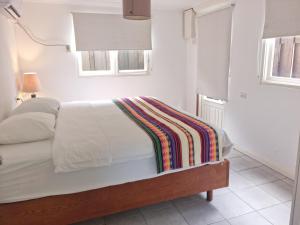 een witte slaapkamer met een bed met een kleurrijke deken erop bij Aruba SeaScape Apartments in Palm-Eagle Beach +19 foto's