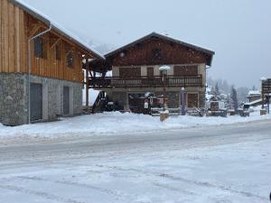 a large wooden building with snow on the ground at Changalan II in Vars