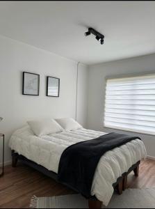 a white bedroom with a large bed and a window at Casa Bulnes in Constitución