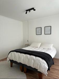 a white bedroom with a bed with a black blanket at Casa Bulnes in Constitución