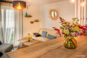 ein Wohnzimmer mit einer Vase aus Blumen auf einem Holztisch in der Unterkunft RÉF 218 PLOEMEUR belle rénovation pour ce type 2 au centre in Ploemeur