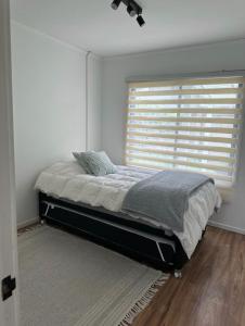 a bedroom with a bed and a window with a blind at Casa Bulnes in Constitución