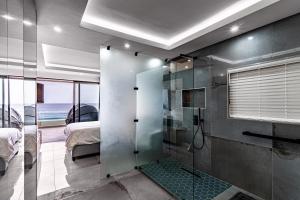 uma casa de banho com um chuveiro e um quarto com uma cama em Modern Chic Beachfront Apartment em Ballito