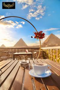 Comfort Pyramids&Sphinx Inn في القاهرة: كوب من القهوة و مزهرية مع وردة على طاولة