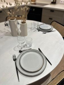 una mesa blanca con platos, tenedores y vasos. en La Casa Samat en Vertou