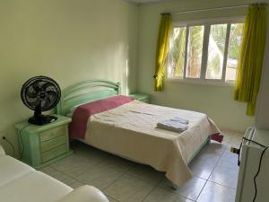 Chalet Sol Nascente في لورو دي فريتاس: غرفة نوم بسرير مع مروحة ونافذة