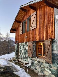 eine Hütte mit einem Fenster und einem Stuhl davor in der Unterkunft Chalet d'alpage Le Lauzeron in Aiguilles