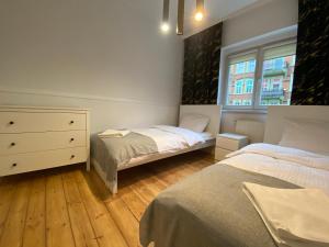 a bedroom with two beds and a dresser and a window at Tabago Studio 14 in Nysa