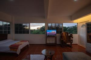 - une chambre avec un lit, une télévision et des fenêtres dans l'établissement Cenote Popol Vuh, à Leona Vicario