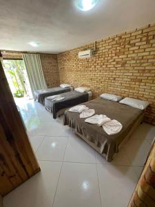 a room with three beds and a brick wall at Fazenda Momm - Pousada e Eventos in Camboriú