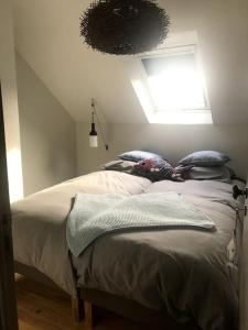 ein Schlafzimmer mit einem Bett mit Kissen und einem Fenster in der Unterkunft Petite maison bretonne : P'ty Penty in Plougastel-Daoulas