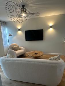 a living room with a white couch and a flat screen tv at La Casa Samat in Vertou