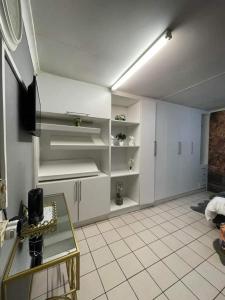 Una cocina con gabinetes blancos y una mesa de vidrio. en P&l exclusive beauty parlour, en Johannesburgo