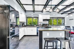 une cuisine avec des armoires blanches et un comptoir avec des tabourets dans l'établissement Loon Lodge, à Readfield